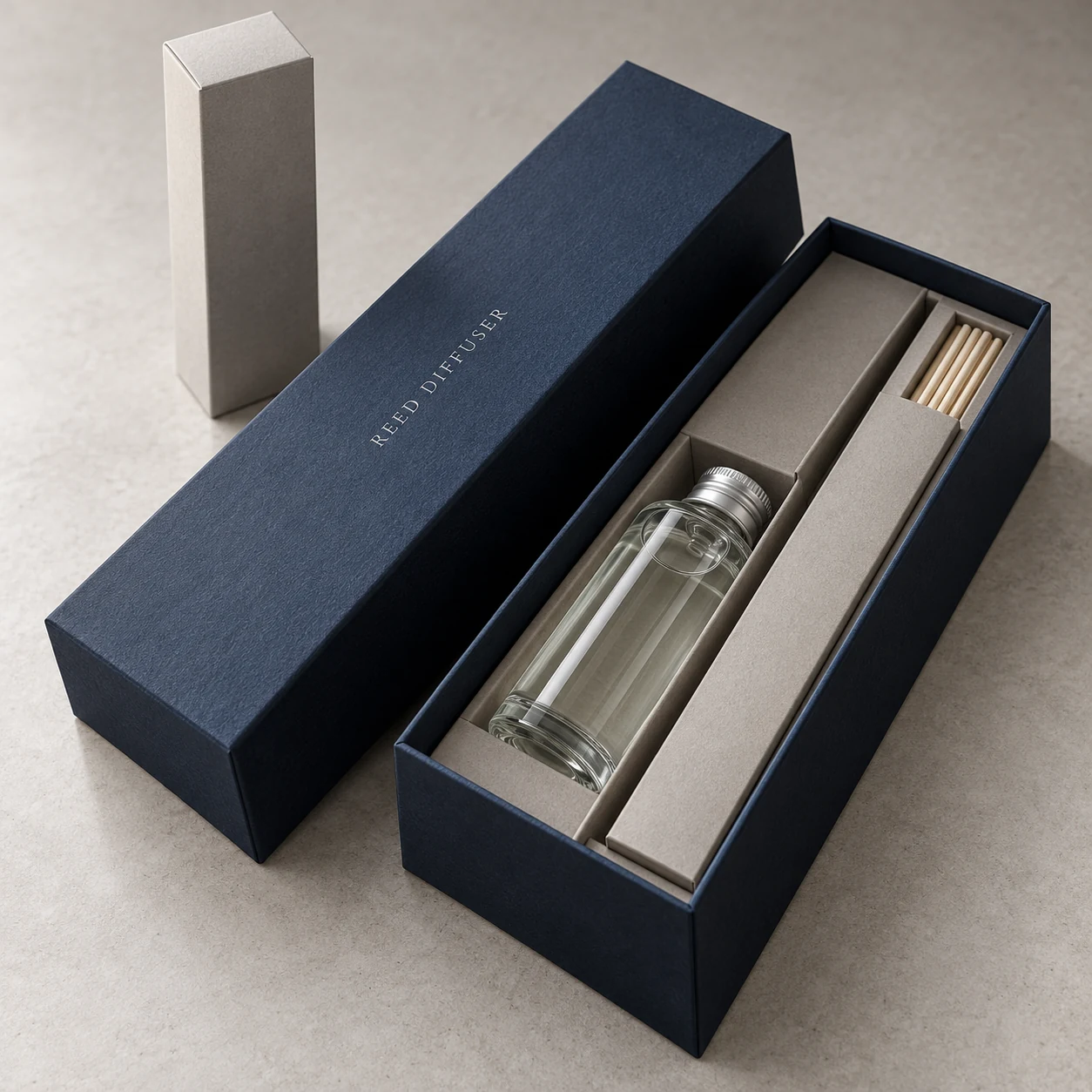 Illustrative ink-blue rigid diffuser gift box with a separate lid, fitted bottle cavity and reed sleeve